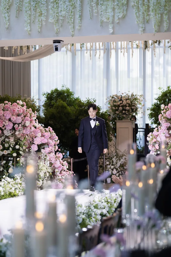 촛불과 플라워 장식이 늘어선 통로를 걸어오는 신랑 단독 입장 장면